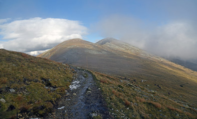 autumn Nizke Tatry mountains in Slovakia with hiking trail, hills covered by mountain meadow and stones and blue sky with clouds © honza28683