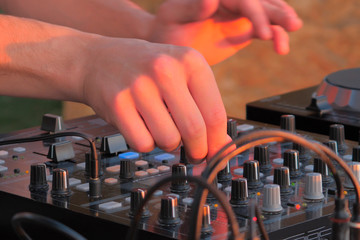 Hand of DJ controlling turntable console mixer. DJ playing music