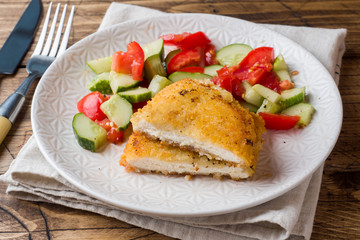 Fototapeta na wymiar Chicken cutlet and cucumber salad with tomatoes on a wooden table