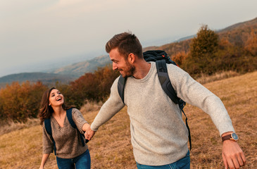 Young couple enjoying hiking in nature They are holding hands and laughing.