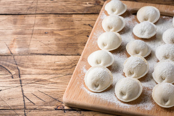 Fototapeta na wymiar Raw dumplings on a wooden chopping Board in the kitchen Copy space