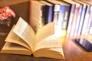 an open book with open pages and mobile phone and flower and books in background a relaxing scene in brown toning