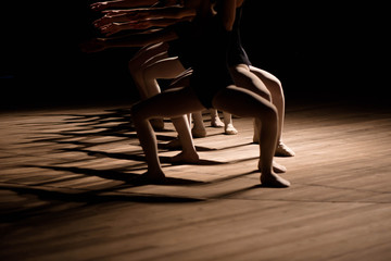 Young ballerinas practicing a choreographed dance all raining their arms in graceful unison during practice at a ballet school