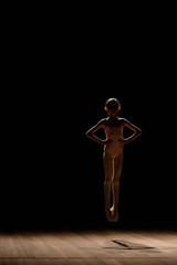 Young excited girl jumping in the studio or on the stage.