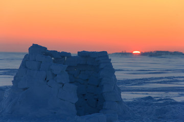 The igloo snowy house is unfinished and is empty at sunset in the middle of a deserted snow-covered...