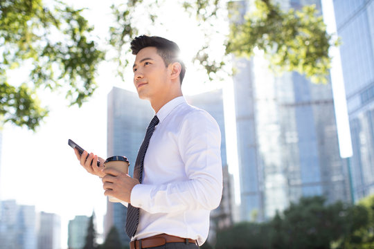 Confident young businessman using smart phone