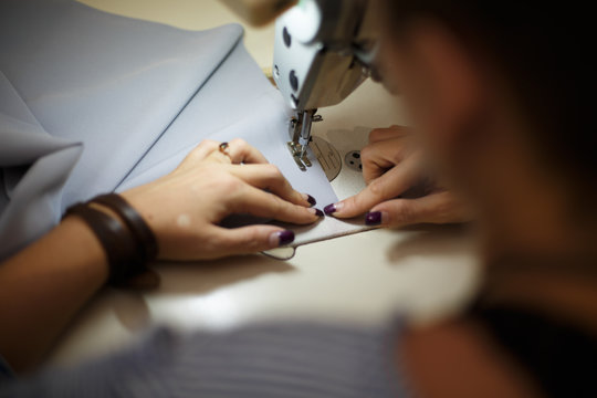 Workplace seamstress. Tailoring industry. Girl sews on the sewing machine. Factory clothing