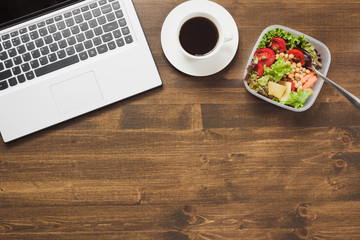 Healthy business lunch in office, salad, coffee on wooden table. Top view with copy space. Concept...