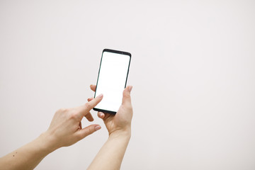 Female hand holding black cellphone with white screen.