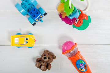 Colorful kids toys on white wooden background.