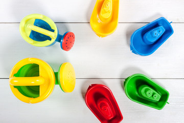Colorful kids toys on white wooden background.