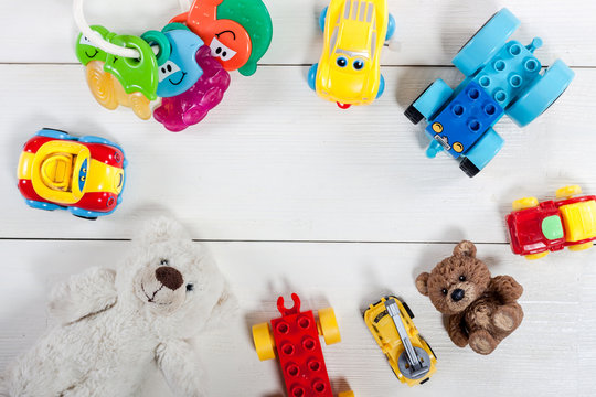 Colorful kids toys on white wooden background.