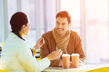 handsome man with girlfriend sitting at table with disposable cups in cafe