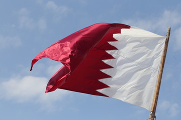 The national flag of Qatar, flying from a flagpole in Doha.