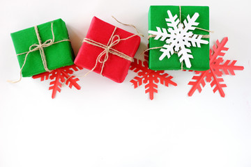 Christmas gifts packed into craft paper of krsny and green color on a white background. Paper snowflakes