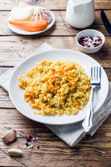 Vegetarian Oriental pilaf with rice and vegetables on a wooden table.