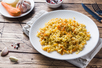 Vegetarian Oriental pilaf with rice and vegetables on a wooden table.