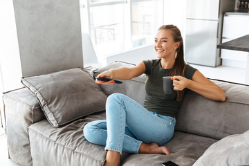 Obraz premium Cheerful young woman sitting on a couch at home
