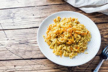 Vegetarian Oriental pilaf with rice and vegetables on a wooden table.