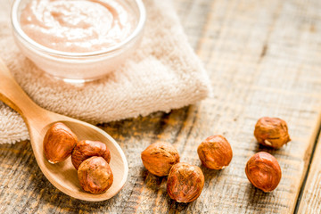 cosmetic set with hazelnut scrub on table background