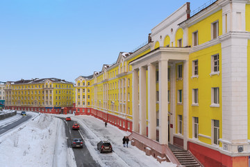 Naklejka premium Komsomolskaya street in Norilsk city. Krasnoyarsk region, Russia. Yellow buildings in the architectural style of the Soviet neo-classicism.