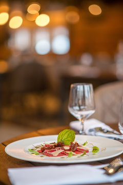 exclusive carpaccio of beef fillet served on white plate with parmesan, pesto and herbs, product photography for modern gastronomy