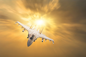 Furious military fighter jet with fire from engines flies in the orange sunset sky.