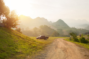 Pickup trucks is parking in camping area  ,beautiful of view with sunlight in the morning  and mountain background at Pakchong Thailand. - obrazy, fototapety, plakaty