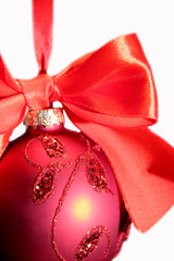 A closeup of a red christmas ball with a big red ribbon isolated on white