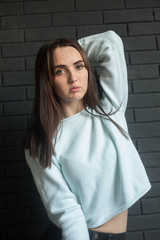 The portrait of a young beautiful lady with dark hair on the dark gray background