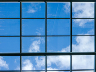 Blue sky with white clouds through the window in the ceiling of a large building