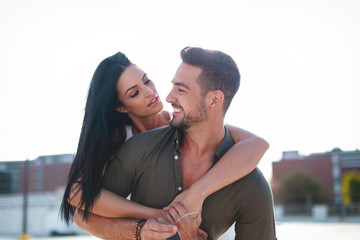 Happy caucasian urban couple doing piggyback at outdoors