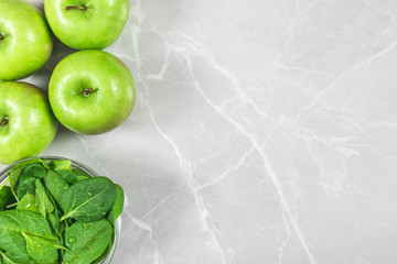 Glass bowl with fresh green  spinach with water drops and four apples. Healthy eating or dieting with copy space.
