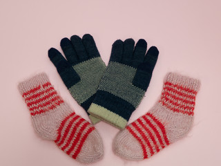 pairs of woolen socks and gloves on pink background. winter must have cloth