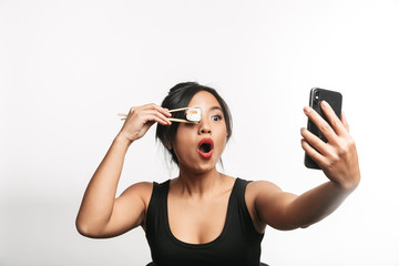 Cheerful young asian woman eating sushi