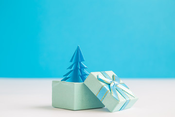 Blue origami christmas tree in form of present on table.