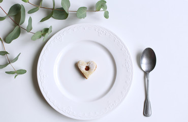 New Year or Christmas table setting with plate, and a spoon, eucalypt and homemade festive sweets. Party decoration. Flat lay, top view.