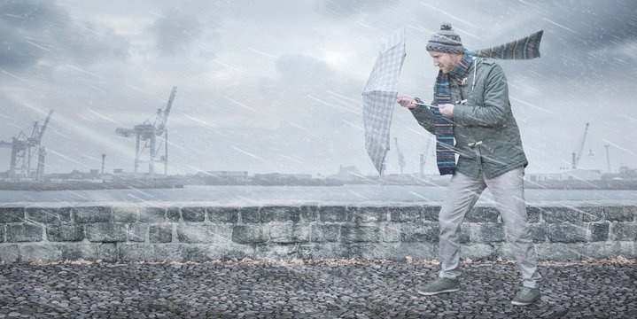 Fu&szlig;g&auml;nger mit Regenschirm stellt sich Wind und Regen