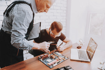 Fototapeta na wymiar Two Men Repairing Hardware Equipment in Workshop.