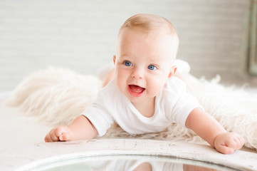 Cute happy 7 month baby girl in diaper lying and playing