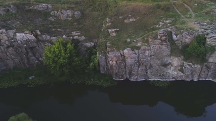 Mountain creek running at a high rocky bank with stones and trees in summer
