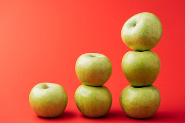 stacks of ripe green apples on red background