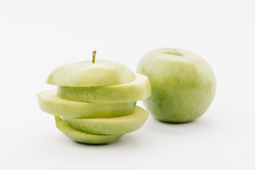 sliced and whole golden delicious apples on white background