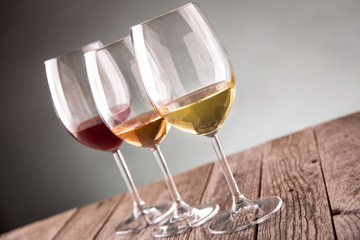 Glasses with white, rose and red wine on rustic old wooden table selective focus
