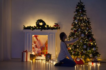 beautiful woman decorates the Christmas tree Garland lights new year holiday