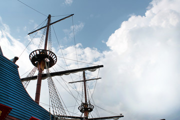 masts of an ancient ship on the background of a sunny sky with clouds