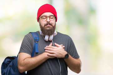 Young hipster man wearing red wool cap and backpack over isolated background smiling with hands on...
