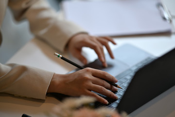 Cropped shot of an unrecognizable business woman working on her laptop at desk in modern office