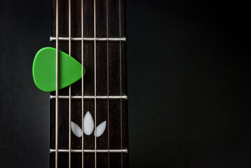 green guitar pick on the fingerboard. copy space