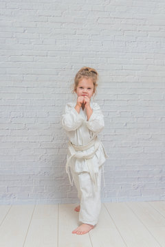 girl, a child in a kimono on karate training works out blows and greeting